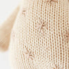 Close-up of a beige hand-knit fabric showing detailed stitch patterns and textures, crafted from Cuddle + Kind Baby Giraffe cotton yarn.