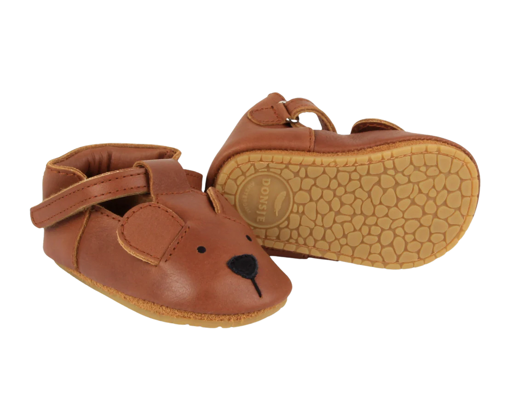 A pair of small brown Donsje Baby Bear Shoes designed to look like bears, featuring bear face details and textured soles.