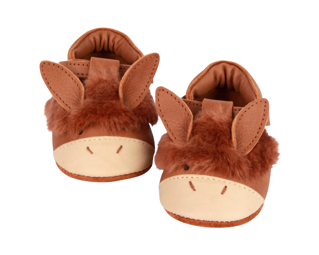 A pair of whimsical children's slippers designed to look like brown donkeys, featuring floppy ears and stitched faces, complete with a velcro fastening strap, isolated on a transparent background.