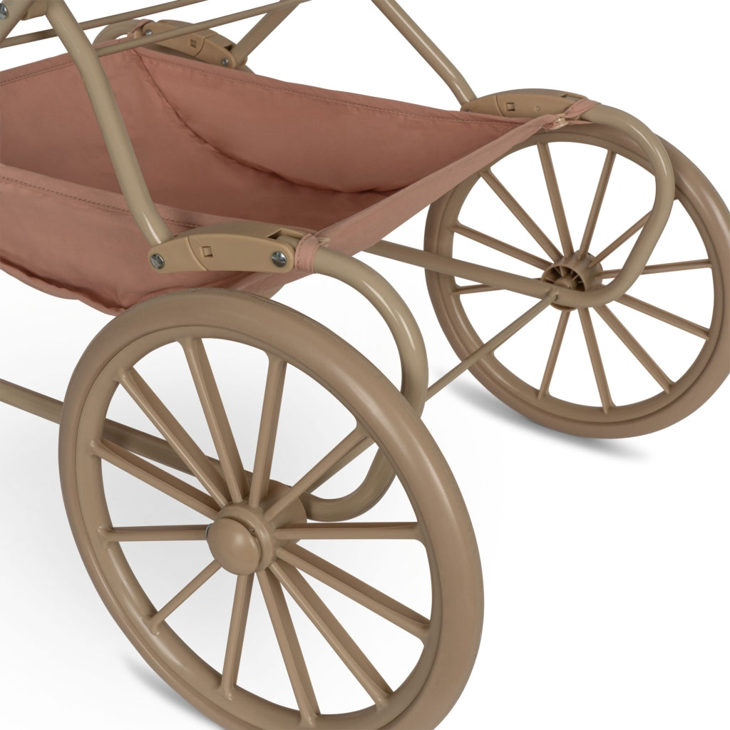 Close-up of a Mahogany Rose doll pram in beige color, featuring large spoked wheels and a fabric hood. The design includes leather accents and a metal frame.