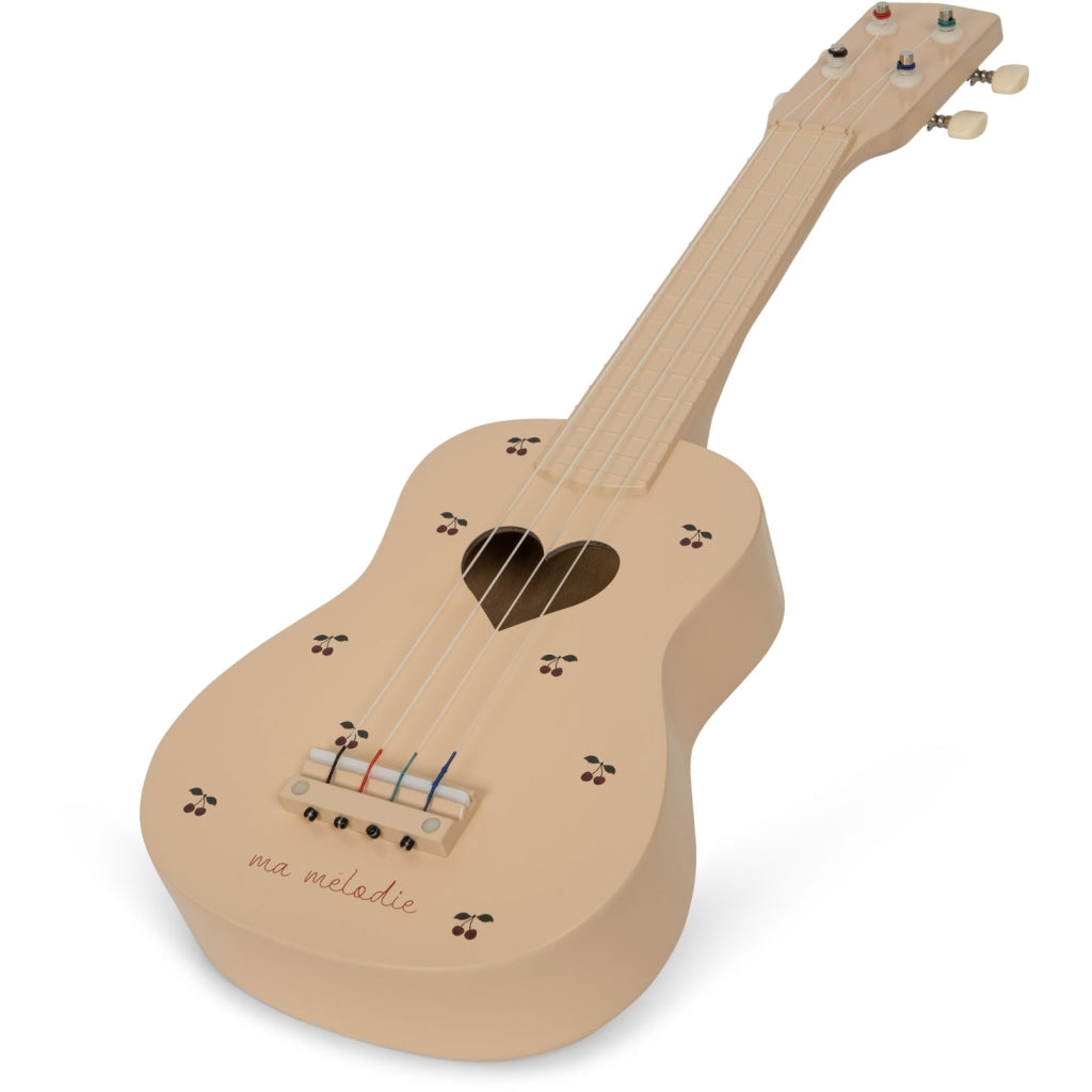 The Wooden Ukulele - Cherry is a small, light beige FSC-certified wooden ukulele with 4 strings, a heart-shaped sound hole, floral details, "ma mélodie" on the body, and simple tuning pegs—perfect for eco-friendly musical play.