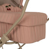 Close-up view of a pink Doll Pram - Mahogany Rose with vertical quilting and a small embroidered cherry design. The bassinet is supported by a beige frame visible to the side and features EVA material wheels.