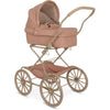 A vintage-style Mahogany Rose doll pram in soft pink with beige details, featuring large classic wheels, a pleated canopy, and a plush interior with a teddy bear inside.