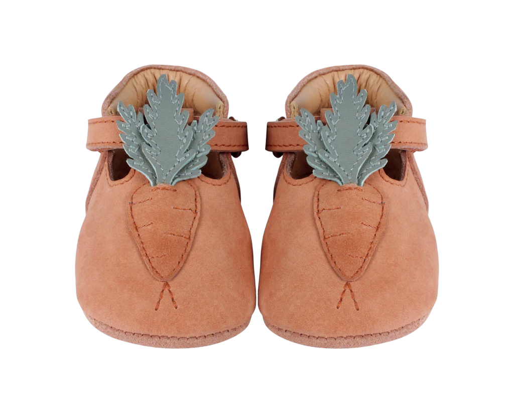 A pair of Donsje Baby Carrot Shoes in tan with a decorative oak leaf accent stitched on each toe, displayed against a black background.