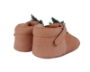 A pair of Donsje Baby Carrot Shoes, handmade from 100% premium leather, with decorative frills and a velcro strap, isolated on a black background.
