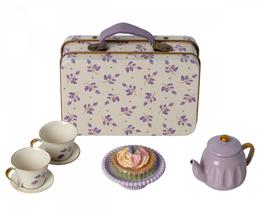 A children's tea set from the Maileg Farmhouse - Fully Furnished featuring a patterned suitcase, a lavender teapot, two cups, and a plate with a decorative pastry, all set against a plain background.