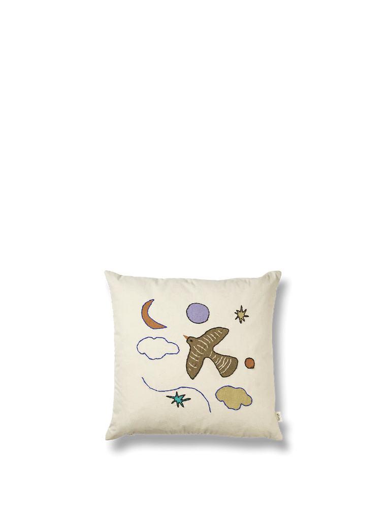 The Ferm Living Naïve Cushion - Bird is a square, cream-colored kids cushion made from organic cotton, featuring hand-embroidered designs of a brown bird, moon, clouds, stars, and abstract shapes on a plain white background.