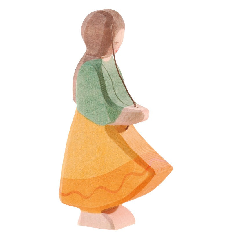 The Ostheimer Goose Girl is a handcrafted wooden figurine featuring a girl with long brown hair in side profile, wearing a green top and yellow skirt with an orange wavy line—perfect for non-toxic toy collections.