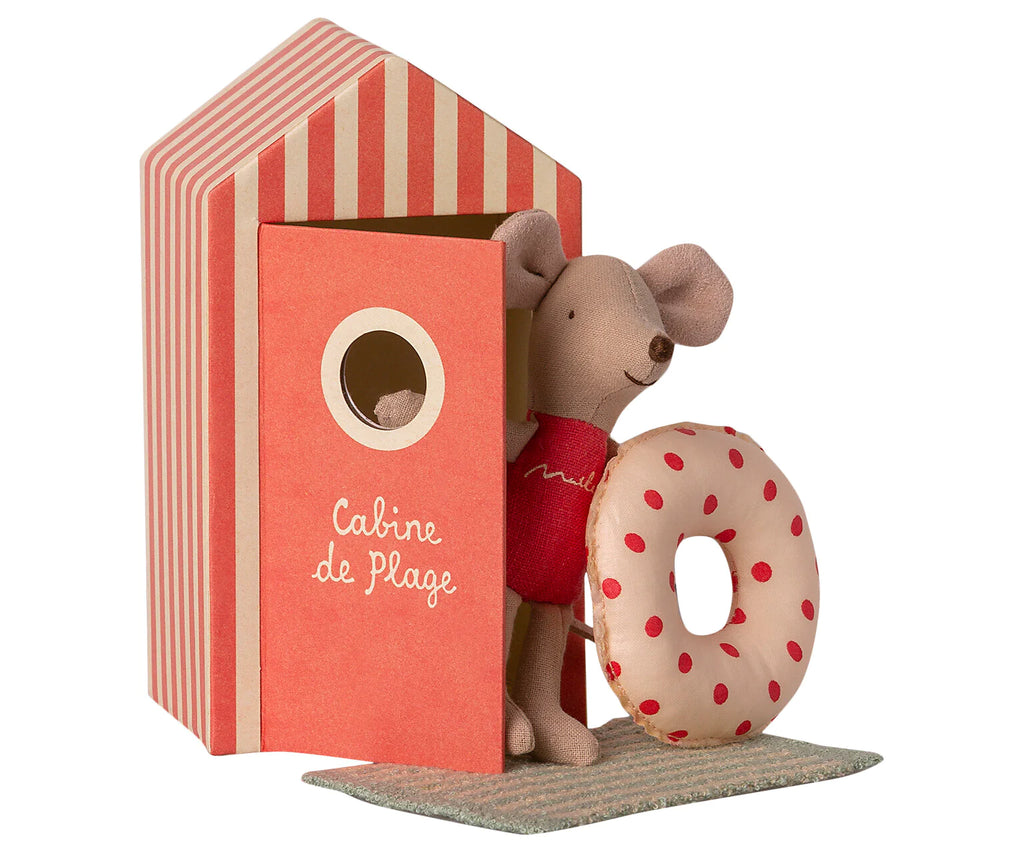 A decorative display featuring the Maileg Beach Mouse - Little Sister next to a red and white striped beach house labeled "cabine de plage," holding a lifebuoy. The scene is set on a sand-like textured mat.
