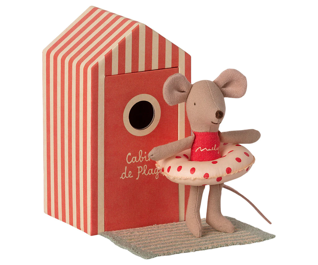 A Maileg Beach Mouse - Little Sister wearing a swimsuit and a lifesaver, standing next to a striped red and white beach house labeled "cabine de plage".
