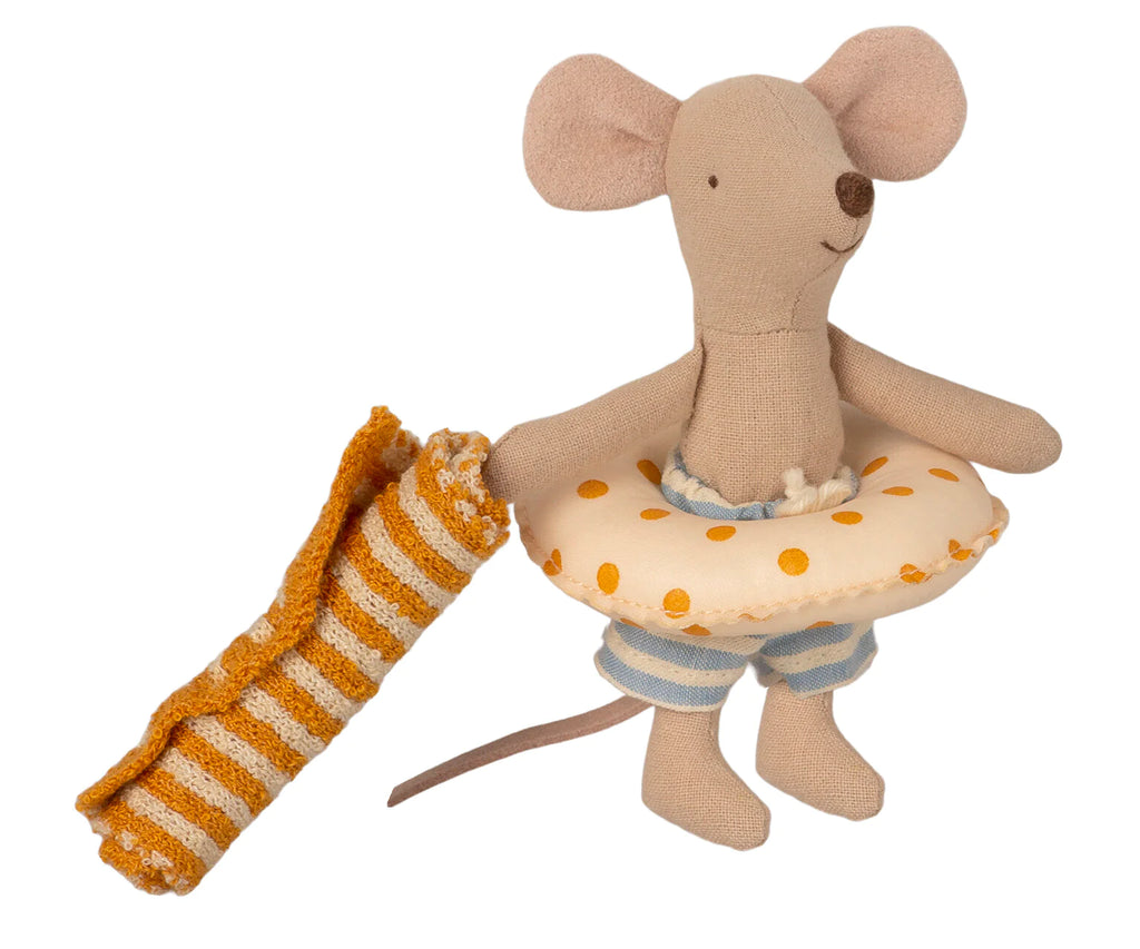 A Maileg Beach Mouse - Little Brother wearing blue-striped shorts and a yellow polka dot swim ring, holding a rolled-up orange and white striped towel. Perfect for beach house decor or as playful accessories, the toy has a happy expression with a stitched nose and ears, ready for vacation time.