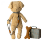 A Maileg Puppy Accessories - Blue stands upright. Beside it are a beige bone-shaped toy and a small vintage-style suitcase with a Maileg print floral pattern.