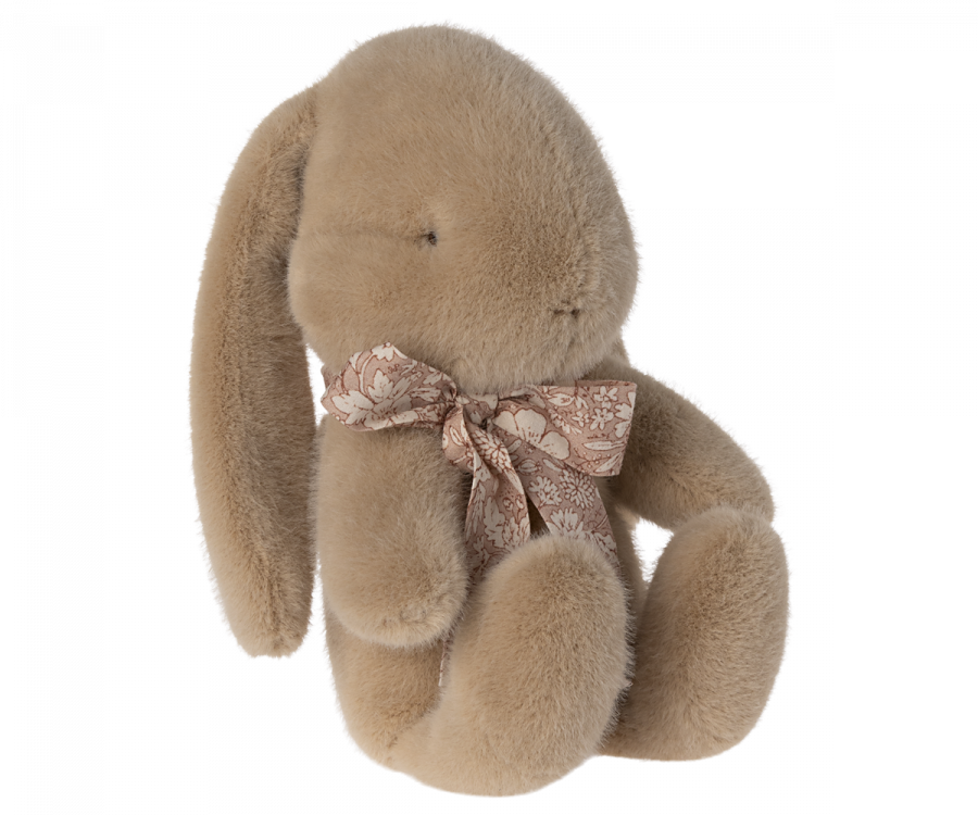 Light brown plush bunny with light pink floral bow around its neck. 