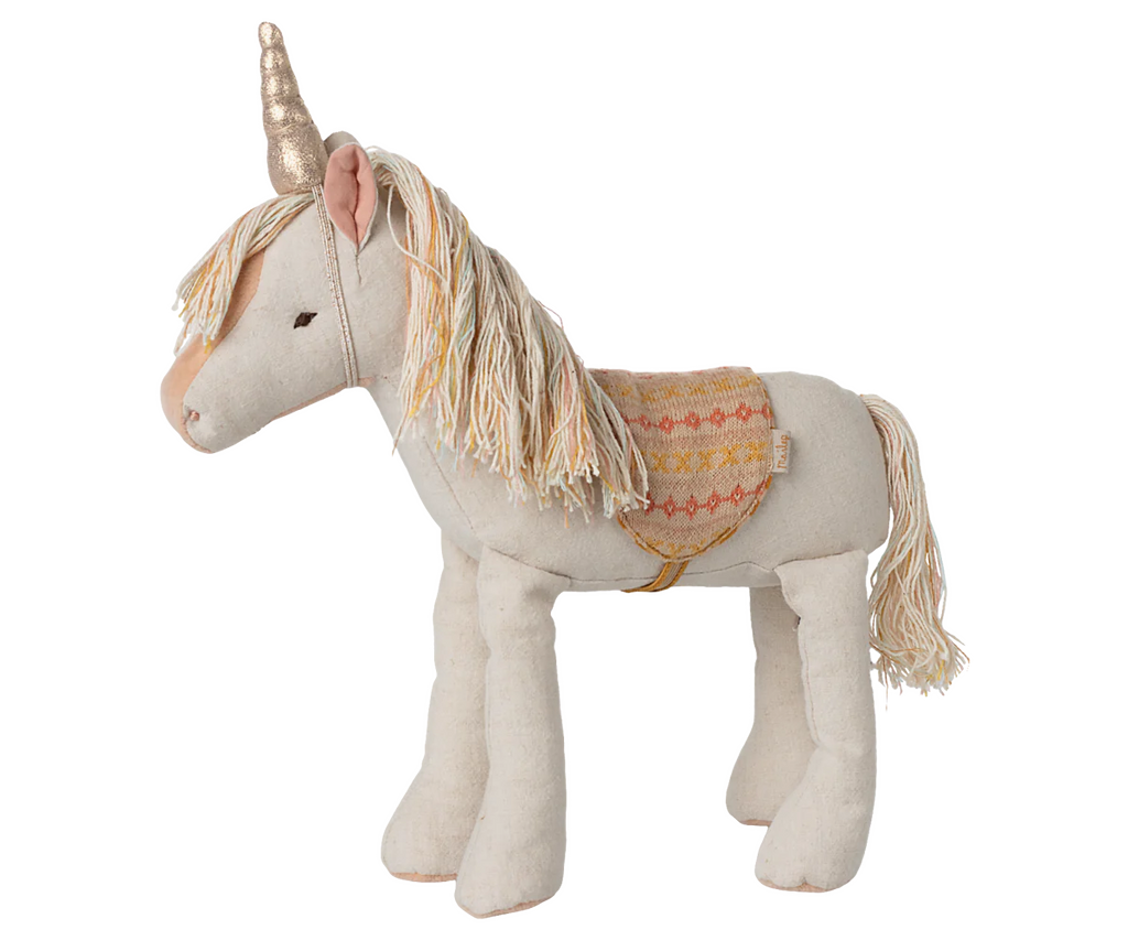 The Maileg Unicorn, Medium features cream linen-cotton fur, a golden horn, pastel yarn mane and tail, and an orange patterned fabric saddle. This colorful unicorn stands on all four legs against a neutral background.