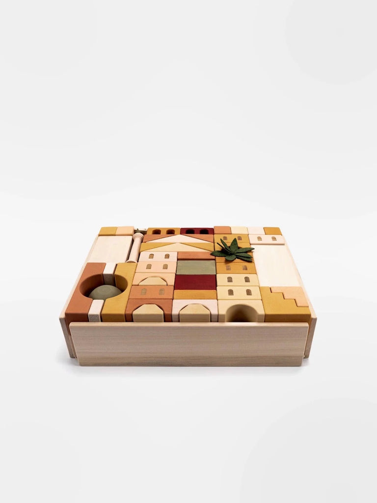 A Sabo Concept Italian Ancient City Blocks puzzle in a tray, featuring various abstract shapes in different shades of brown and beige, with a Michelangelo's David statue-shaped piece in green laid on top, set against a white background.