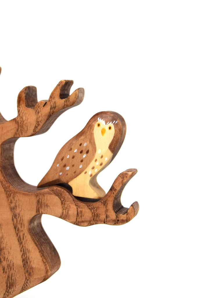 The Handmade Wooden Little Owl, crafted from sustainable hardwood with painted details and perched on a carved wooden tree branch, is a charming woodland accent for your space.
