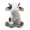 A cuddly Steiff cow stuffed animal with black and white coloring, sitting upright on a white background, featuring a Steiff button in ear.