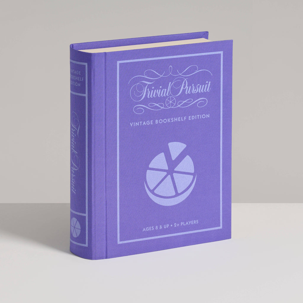 A purple hardcover Board Game: Trivial Pursuit Vintage Bookshelf Edition stands upright, featuring a pie chart on the cover. Ideal for ages 8+ and two or more players, it's perfect for fans of question and answer games.