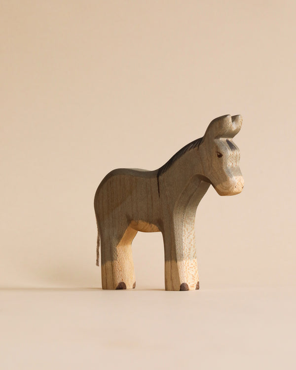A Handmade Holzwald Donkey standing against a plain, light beige background, showcasing visible wood grain and a smooth finish typical of sustainable wooden toys.