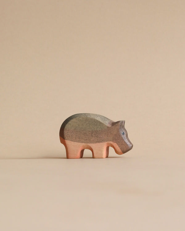 A Handmade Holzwald Small Hippo wooden figurine standing against a beige background, showcasing natural wood grain and a smooth finish.