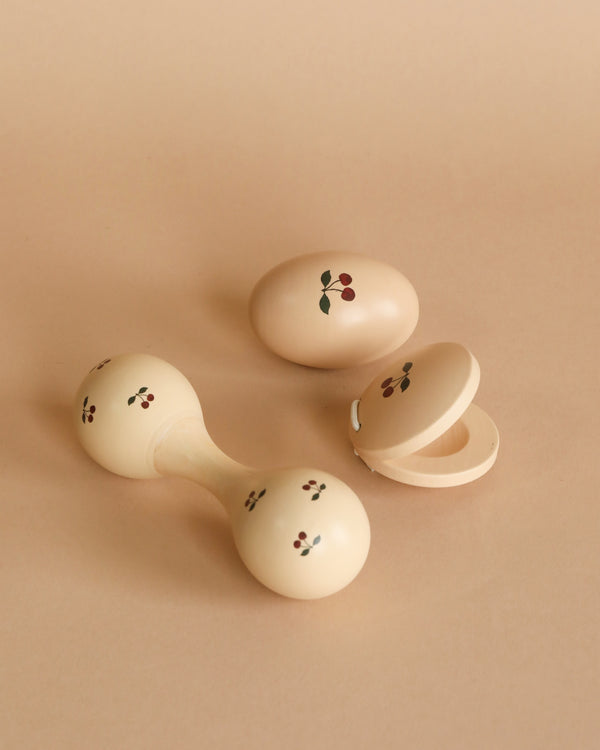 Three Konges Sløjd Wooden Music Sets - Cherry with floral patterns on a beige background, one open showing its hollow interior, crafted from FSC-certified beech wood.