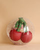 A glass paperweight with a realistic Inflatable Cherry Beach Ball design inside, featuring vibrant red color and green detailing, set against a plain beige background.