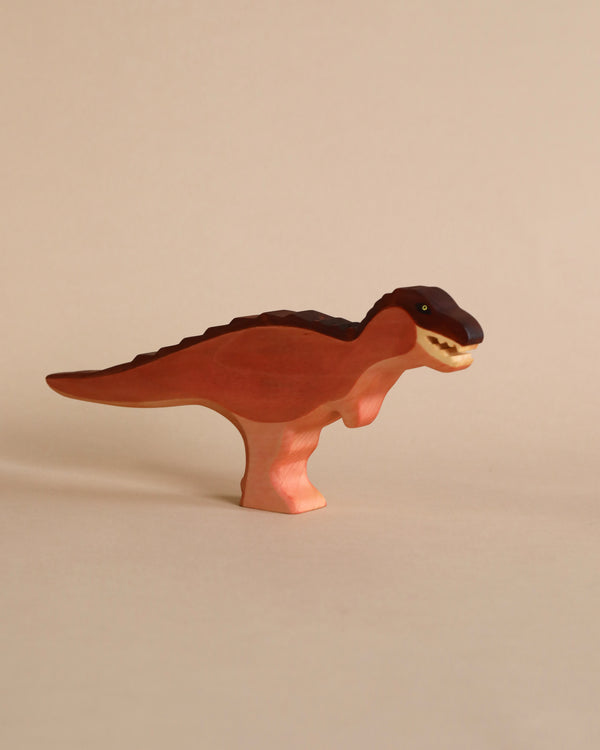A Handmade Holzwald T-Rex Maroon stands isolated on a light beige background, featuring intricate carved details and a smooth, glossy finish in shades of red and brown.