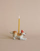 A Golden Retriever Cake Topper, designed to hold a slender yellow candle on its back, is set against a soft beige background. The candle is lit, adding