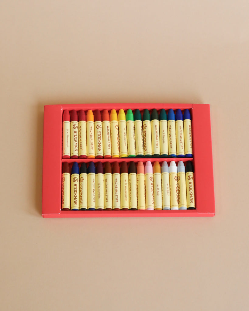 A box of thirty-two assorted Stockmar Wax Stick Crayons, arranged neatly in their packaging, displayed on a plain beige background.