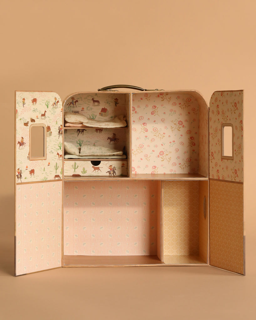 The Maileg SuitCasa wardrobe, designed in vintage style, features open doors with small windows, pastel floral and animal-patterned wallpaper, and shelves for storing mice accessories and bedding (mice and furniture sold separately).