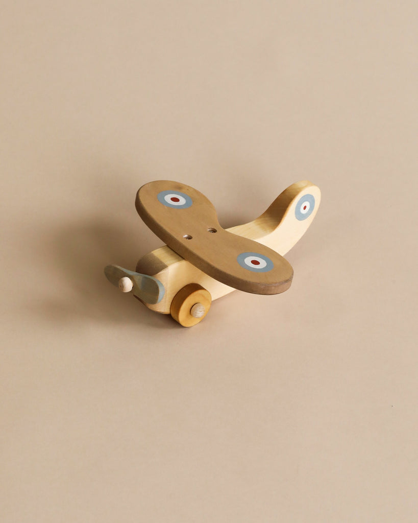 Wooden plane with light blue propeller, light brown wings with blue, white and red circles on each wing. Natural color wooden wheels.