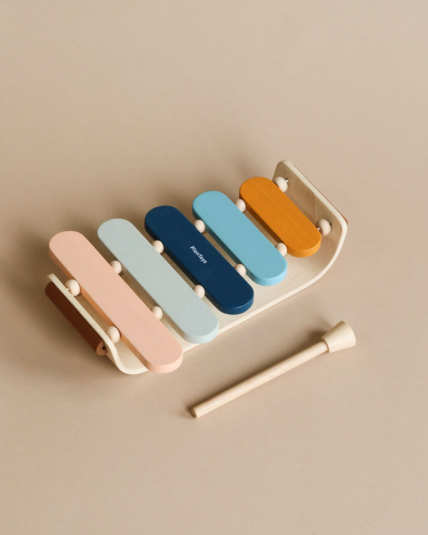 A colorful PlanToys Xylophone Toy with pastel bars and two drumsticks set against a neutral background.