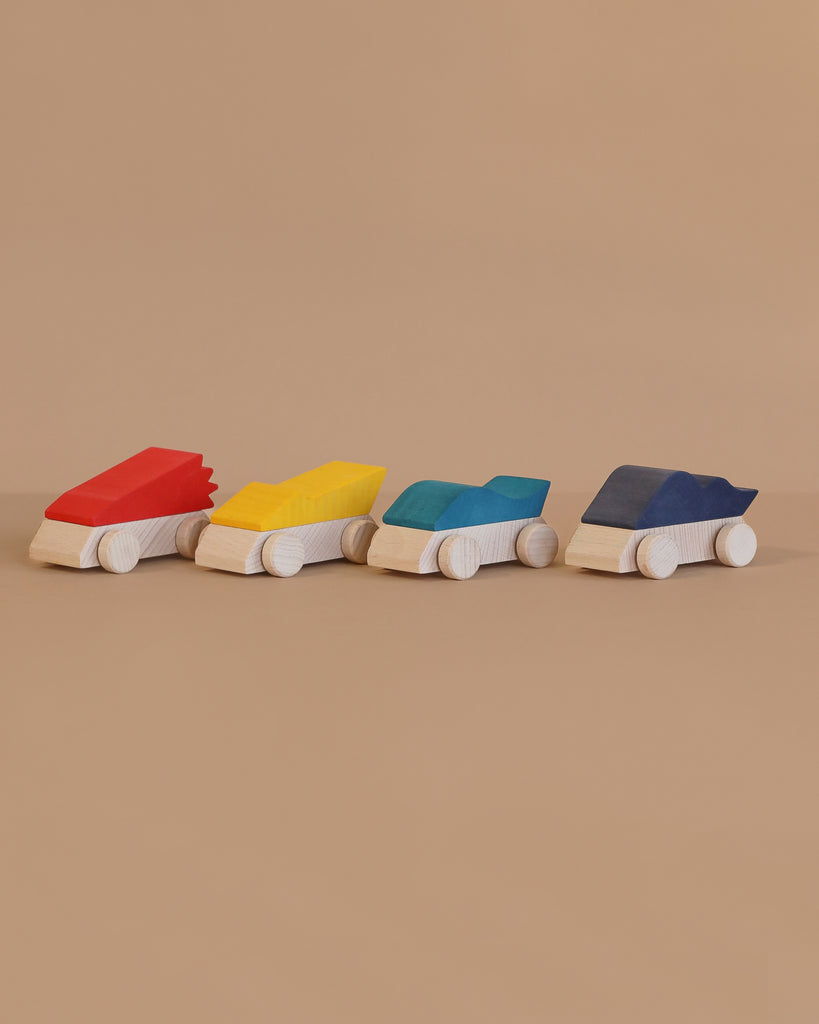 The Lubulona Wooden Pack of 4 Supercars features eco-friendly wooden race cars with white bases and vibrant red, yellow, blue, and dark blue tops, lined up stylishly on a beige surface against a beige background.