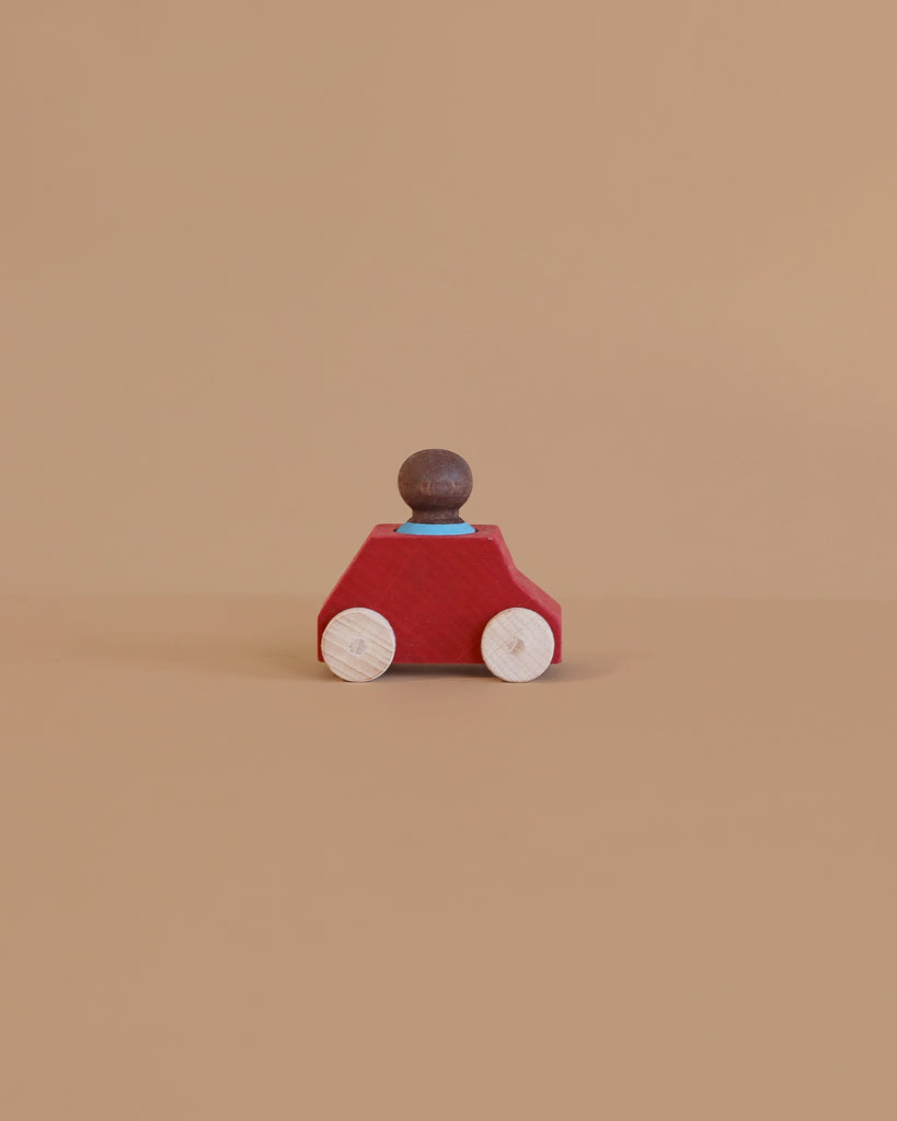 The Lubulona Wooden Car with Figure - Red features a red body, natural wood wheels, and a peg person driver—an eco-friendly toy that sparks imaginative play for kids.