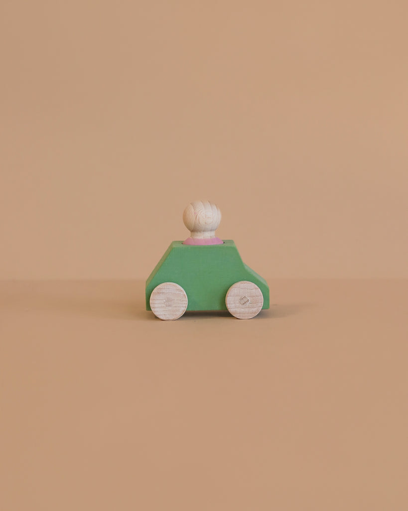 The Lubulona Wooden Car with Figure - Mint is a small, minimalist wooden toy car featuring a mint green body, white wheels, and a round white peg driver—an ideal eco-friendly kids toy set against a plain beige background.