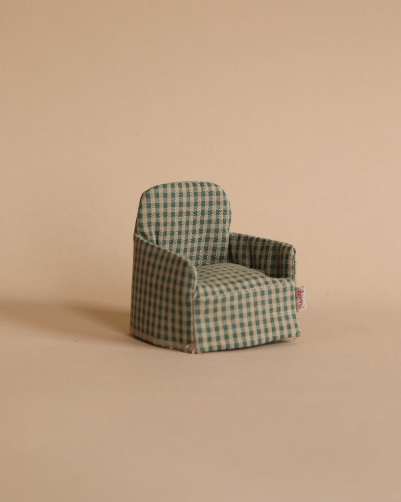 The Maileg Cozy Christmas Set features a small green and beige checkered armchair, perfectly sized for a Maileg Winter Ski Mouse, displayed against a light beige background and ideal for dollhouse setups.