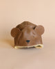 A brown Donsje Leather Classic Hat - Bear shaped like a bear's head, with round ears and a sheep wool lining, set against a soft beige background.