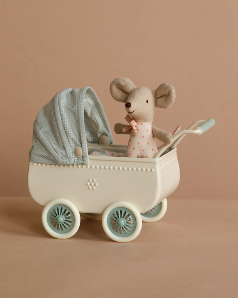 The Maileg Sister’s Day Out features Big Sister Mouse in a pink polka dot dress sitting in a white vintage pram with blue wheels and a blue gingham canopy, set against a plain beige background.