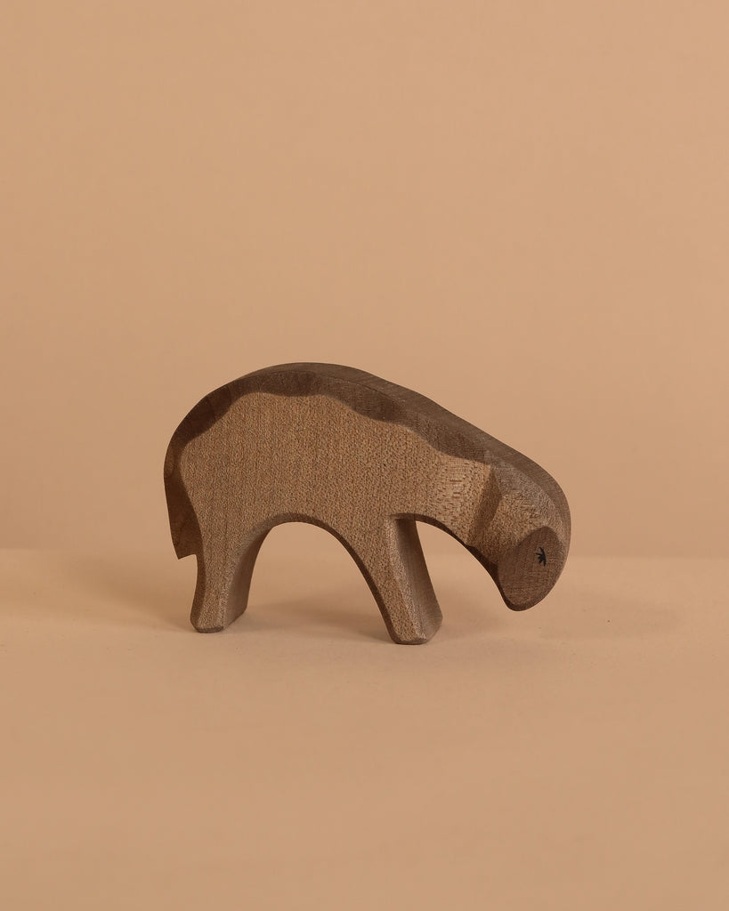 The Ostheimer Bown Sheep - Eating is a small, minimalist wooden animal sculpture, handcrafted for imaginative play, shown on a light beige surface with a matching beige background.