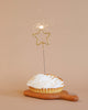 A freshly baked lemon meringue pie on a wooden paddle, adorned with Meri Meri Gold Sparkler Star Candles on a neutral background.