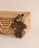 A small brown Senger Naturwelt stuffed animal - Baby Beaver standing next to a woven wicker basket on a beige background.