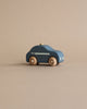 A simplistic wooden police car crafted from responsibly sourced beech wood, painted in dark blue with visible wood grain rotating wheels and minimalistic white detailing, positioned on a smooth beige background.