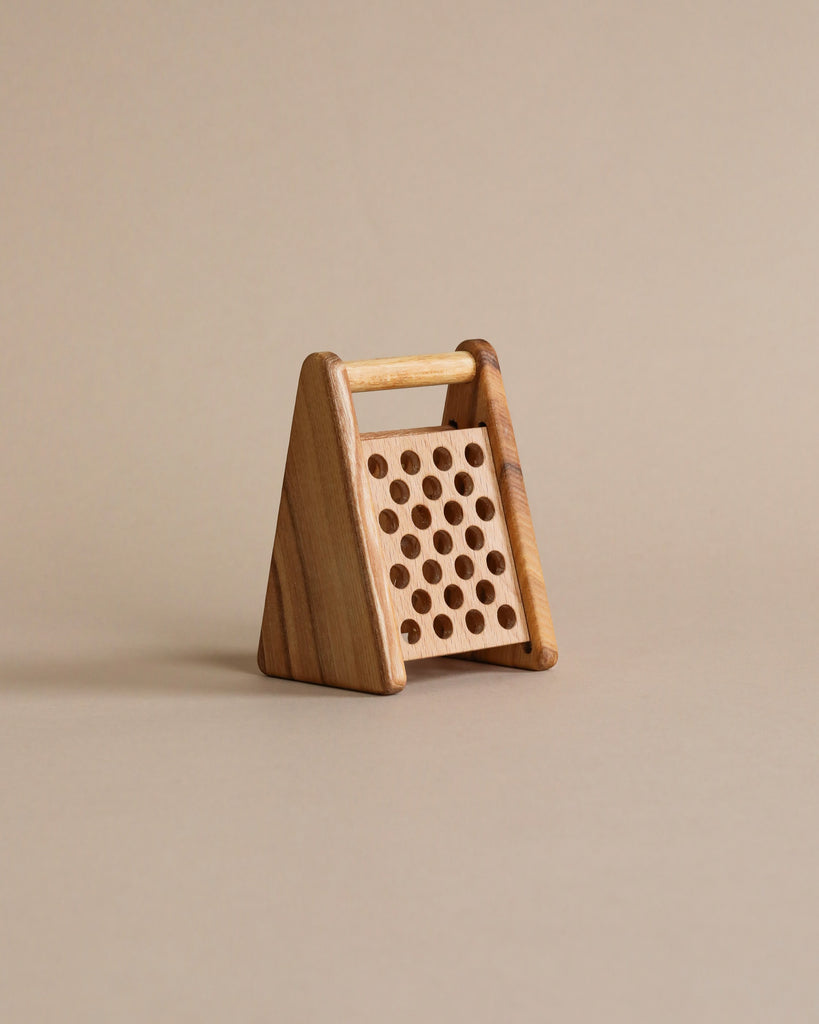 Wooden pretend play cheese grater. Beige background.
