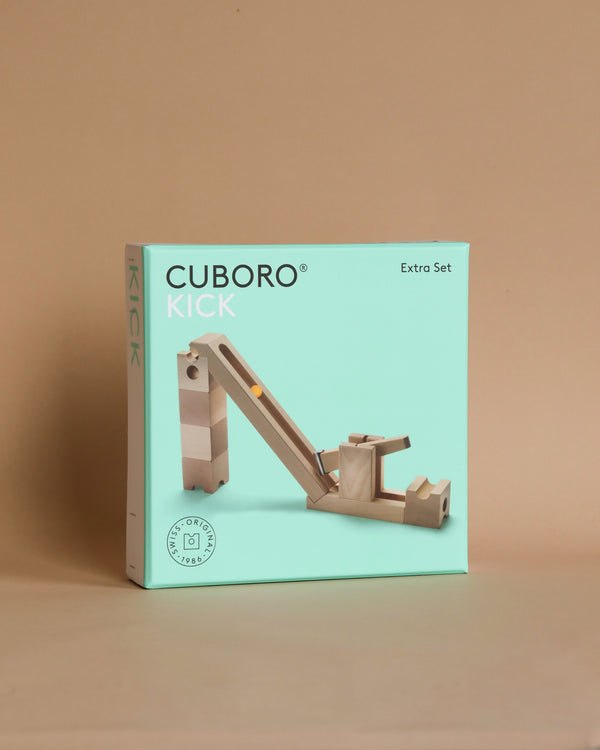 A Cuboro Kick Marble Run Extra Set featuring a setup with wooden blocks, displayed against a plain beige background. The design showcases components set on and around the box.