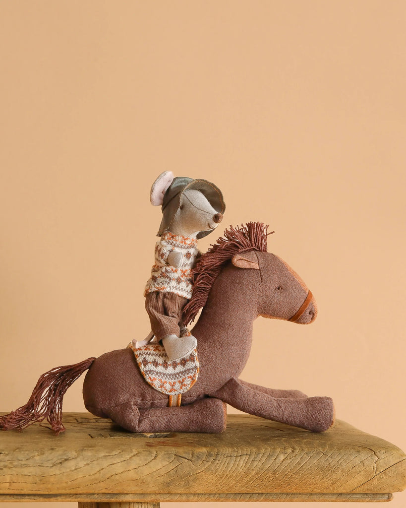 Maileg Big Brother Mouse & Pony – Western Adventure Set features a mouse in a patterned sweater and hat riding a soft cotton/linen pony, displayed on a wooden surface with a plain beige background.