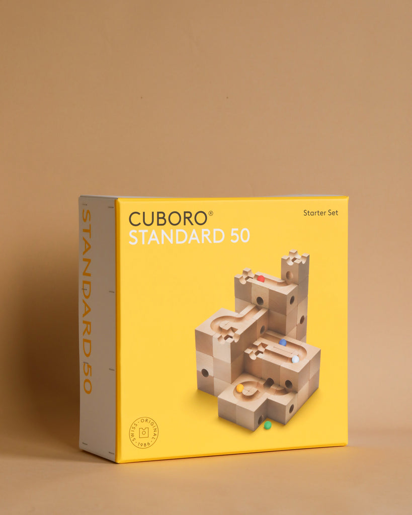A Cuboro 50 Marble Run Starter Set box featuring a wooden marble track system on a neutral beige background. The box is primarily yellow with a clear product image and logos.