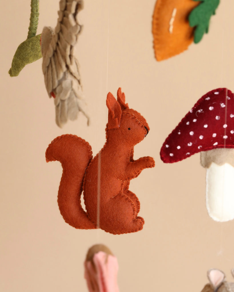 A Handmade Mobile - Forest Friends - Final Sale ornament in a standing pose, designed as part of a nursery mobile, suspended among other colorful forest-themed felt decorations such as leaves and mushrooms.