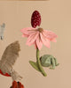 A close-up of a Forest Friends handmade nursery mobile featuring a felt flower in soft pink and a red-polka-dotted beetle, with other felt elements like a bird and leaves softly blurred in the background.