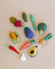 A variety of colorful, handmade soft vegetable set, including a carrot, broccoli, avocado, and others, neatly arranged on a light beige background.