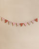 A Maileg garland in shades of pink and patterned gray, hung against a soft beige background.
